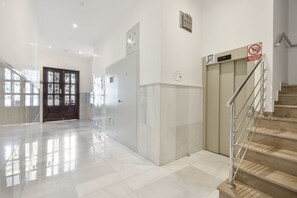Eine saubere, moderne Lobby mit Marmorboden, einer Treppe und einer Tür mit einem Rauchverbotsschild.