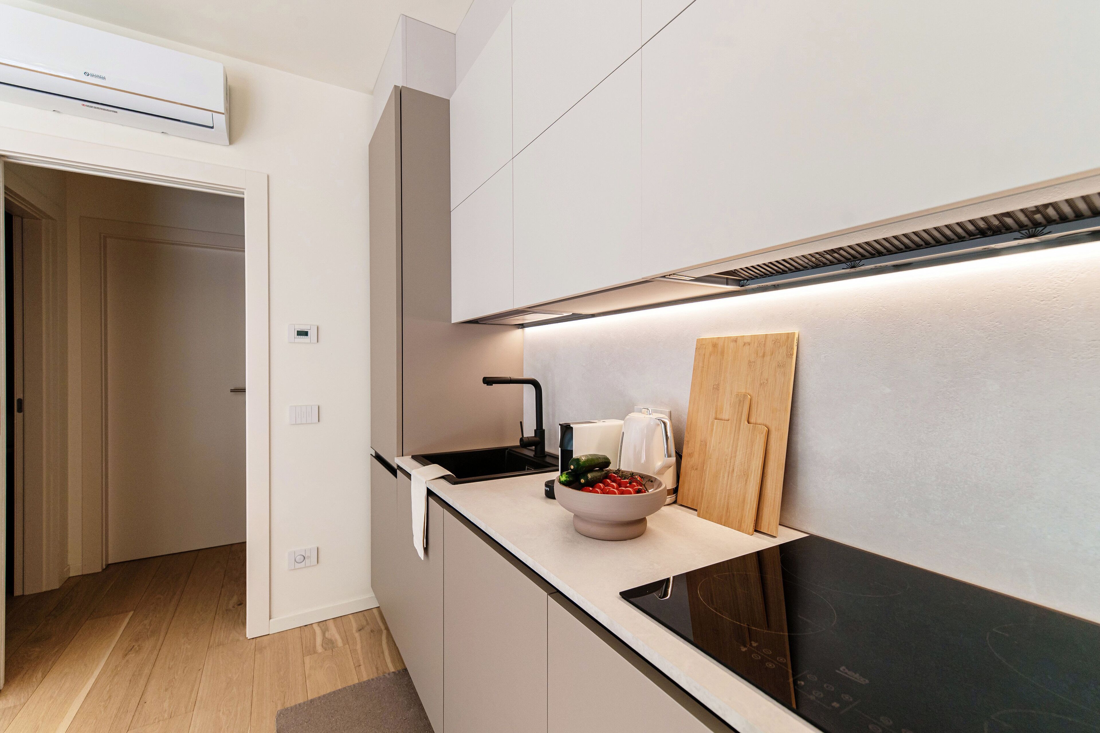 A modern kitchen with a built-in stove, a sink, and a countertop with a bowl of fruit.