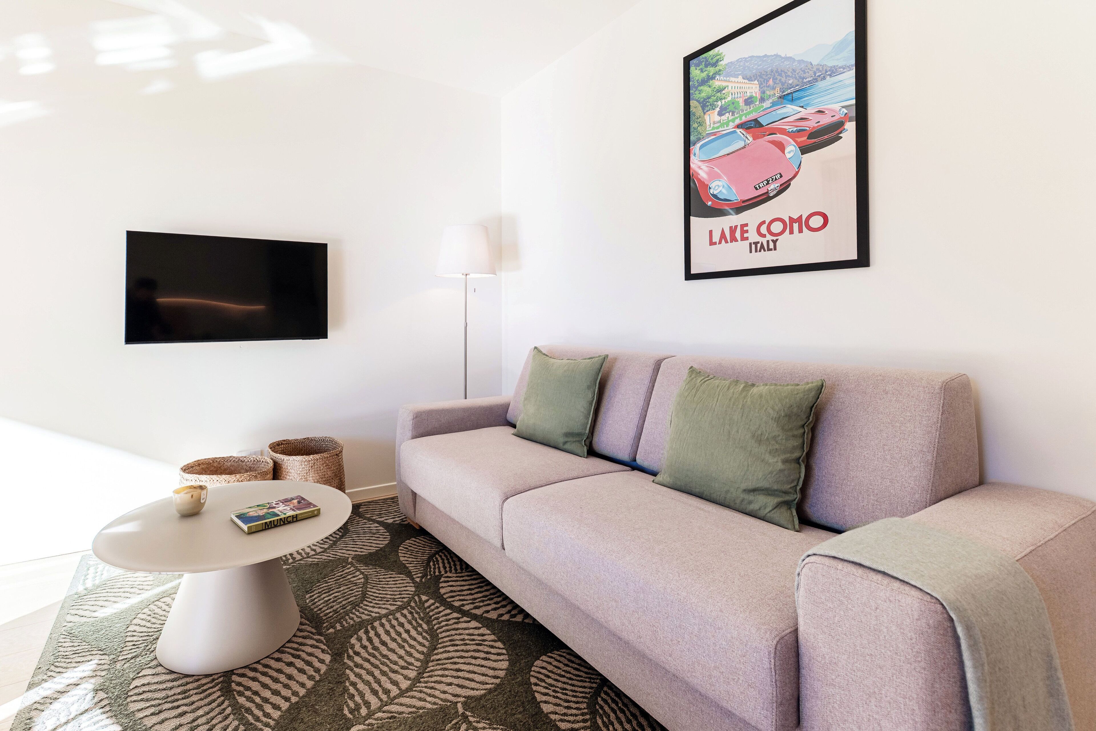 Un salon moderne avec un canapé, une table basse, un téléviseur à écran plat et un tableau encadré accroché au mur.