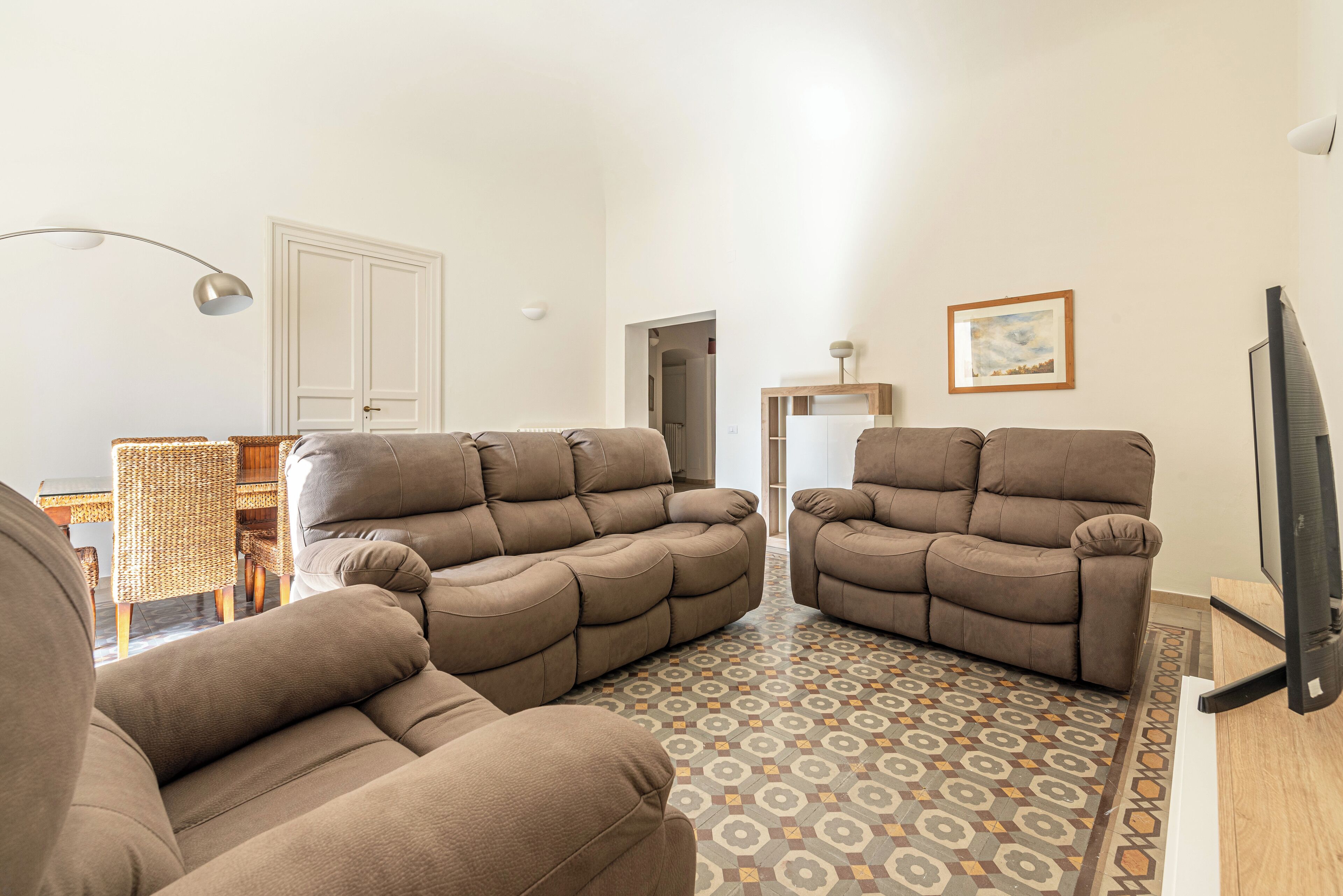 A living room with two reclining sofas, a patterned rug, a television, and a door in the background.