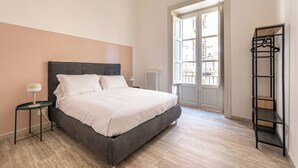 A bedroom with a bed, a bedside table, a radiator, a window, and a shelving unit. - Central City Apartment by Wonderful Italy (Palermo)