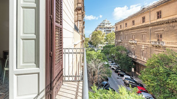 A view from a balcony overlooking a street with parked cars and buildings. - Central City Apartment by Wonderful Italy (Palermo)
