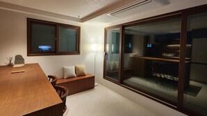 A modern room with a wooden desk, a bench, and a large sliding glass door leading to a kitchen area. - Cozy Café Vibes & Timeless Design — Your Tranquil Seoul Hideaway Awaits (Seoul, , Yongsan-gu)