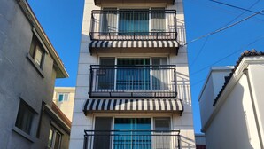A multi-story building with a white facade, a black and white striped awning, and a sign that reads "PAMIS." - Cozy Café Vibes & Timeless Design — Your Tranquil Seoul Hideaway Awaits (Seoul, , Yongsan-gu)