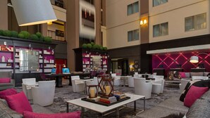 A spacious lobby with a modern design, featuring a central seating area with sofas and armchairs, a coffee table with books, and a large chandelier. - Steps from Galleria Dallas + Dining. Pool. Gym. (Dallas)