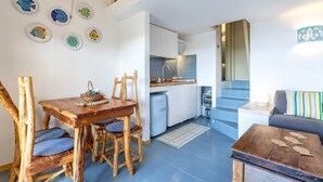 Eine moderne Küche mit weißen Schränken, einem blauen Kühlschrank und einem Essbereich mit Holztisch und Stühlen.