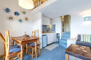 Eine moderne Küche mit weißen Schränken, einem blauen Kühlschrank und einem Essbereich mit Holztisch und Stühlen.