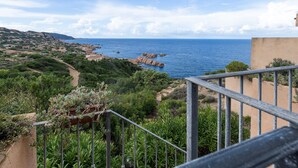 Eine Küstenlandschaft mit freiem Blick auf das Meer, einer Treppe, die zu einem Balkon führt, und umgebender Bepflanzung.