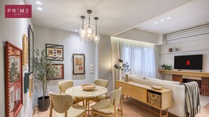 Un salon moderne comprenant un coin repas, un canapé, un téléviseur et des œuvres d’art accrochées aux murs.