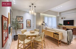 Una sala de estar moderna con comedor, un sofá, un televisor y obras de arte en las paredes.