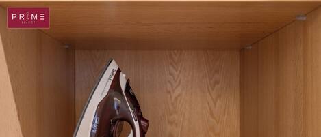 A wooden shelf with a white and brown iron, a white power cord, and a white plug.