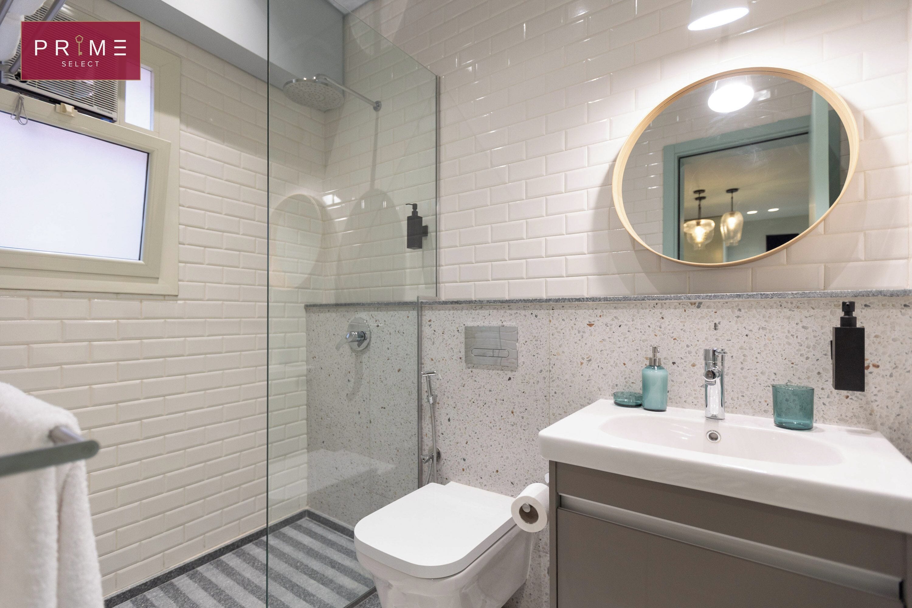 A modern bathroom with a glass-enclosed shower, a toilet, a sink with a mirror, and a towel rack.
