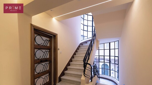 Un escalier moderne avec une rampe en verre, menant à un deuxième étage.