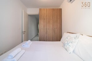 Ein Hotelzimmer mit einem Bett, einem Holzschrank und einem durch eine offene Tür einsehbaren Badezimmer.