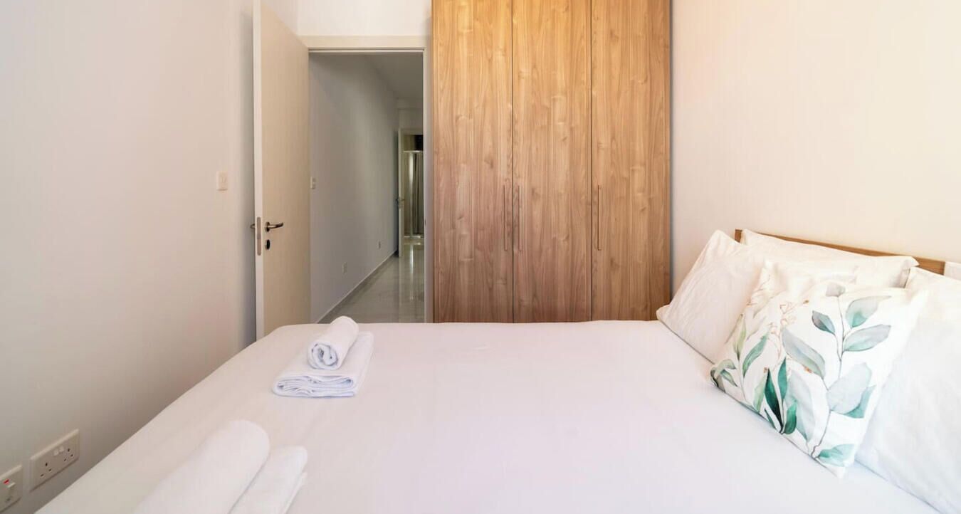 Een hotelkamer met een bed, een houten garderobe en een badkamer door een open deur zichtbaar.
