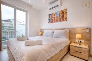 A modern bedroom with a large bed, two bedside tables, and a painting on the wall.