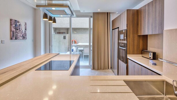 A modern kitchen with a central island, wooden cabinets, and a view into the dining area.