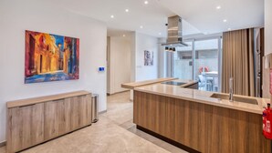 A modern kitchen with a wooden countertop, a stainless steel range hood, and a large window.