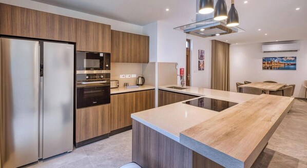 A modern kitchen with wooden cabinets, stainless steel appliances, and a large island. - The Pender LUX HUB - 4BR villa with Pool, WIFI &AC (St. Julian`s)