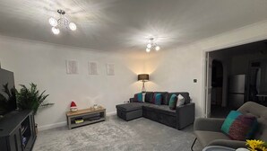 Een moderne woonkamer met een modulaire bank, een salontafel, een tv-meubel en een lamp.