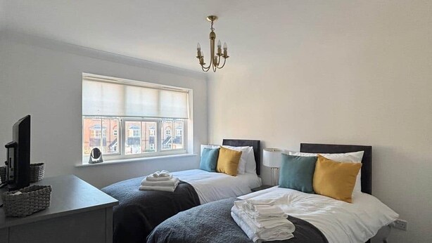 Een slaapkamer met twee bedden, een bureau en een raam.