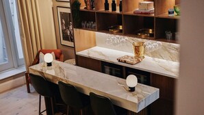 A modern kitchen with a marble countertop, bar stools, and a wine rack. - Beautiful Fulham Townhouse with a bar & pool table (Parsons Green, London, UK)