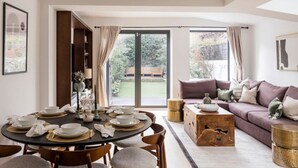 Uma sala de estar moderna com área de jantar, janelas amplas e vista para um jardim.