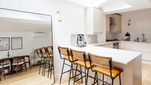 Cozinha moderna com ilha central, banquetas e área de jantar com mesa e cadeiras.