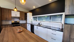 Una cocina moderna con armarios de madera, encimera negra y una mesa de comedor de madera.