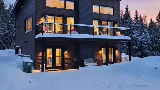 Una casa moderna de dos pisos con un balcón, rodeada de nieve.