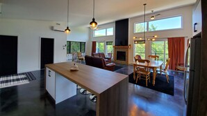 Amplia sala de estar con chimenea, muebles de madera y grandes ventanales con vistas al exterior.