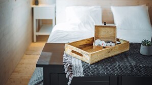 Een knus slaapkamer met een houten hoofdbord, een nachtkastje met verzorgingsproducten en een kleine potplant.