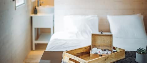A cozy bedroom with a wooden headboard, a bedside table with a tray of toiletries, and a small potted plant.