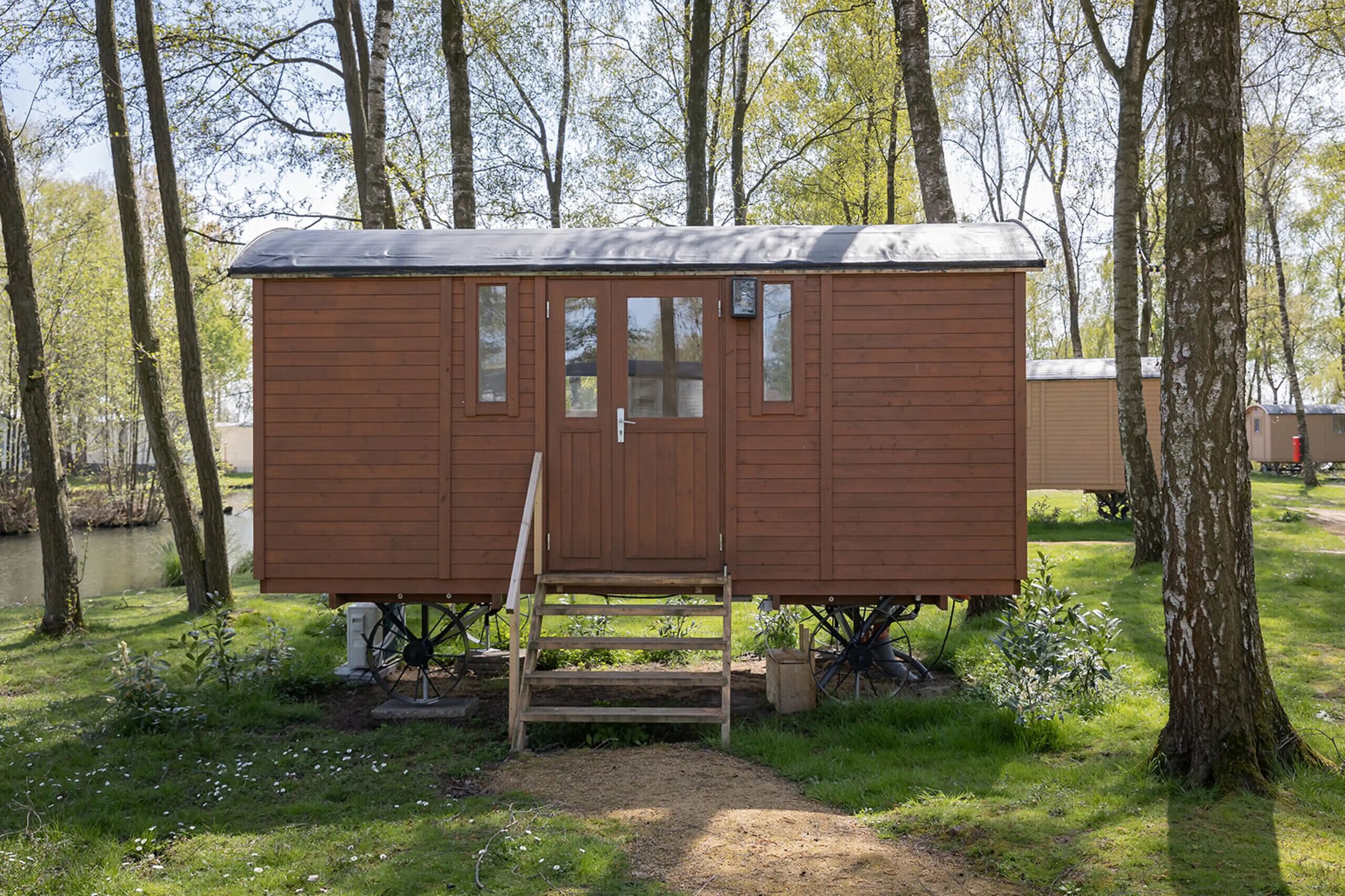 Une cabane en bois avec une porte d’entrée, des fenêtres et un petit porche.