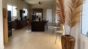 Una cocina amplia con electrodomésticos modernos, una zona de comedor con sillas y un gran ventanal que proporciona luz natural.