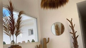 Un interior moderno con un ventanal grande, una lámpara colgante, un espejo redondo y detalles decorativos de madera.
