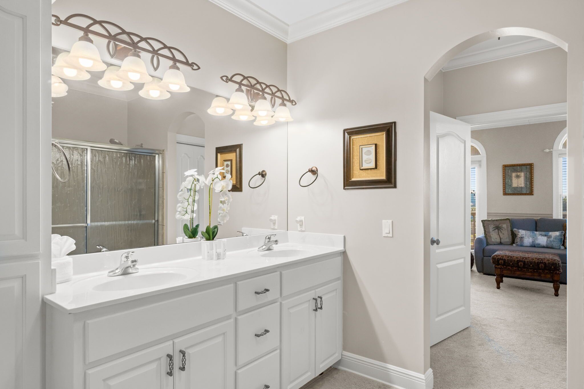 A bathroom with a large mirror, white cabinetry, and a shower area.