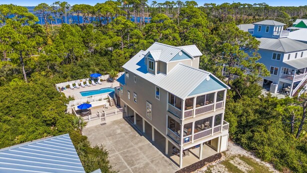 A multi-story house with a pool, surrounded by dense trees and a clear view of the ocean. - Salty Daze- Private pool & hot tub, pet friendly, family friendly! (Cape San Blas)