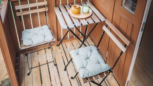 Een houten terras met twee comfortabele stoelen en een kleine tafel met een vaas en kaars.