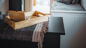 Ein gemütliches Blockhaus-Interieur mit einer hölzernen Bank, einem kleinen Tisch und einem Fenster mit Vorhängen.