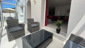 An outdoor patio area with wicker furniture, a glass table, and a potted plant. - Spacious house, all comforts, beach and harbour 100 metres away (Plouescat)
