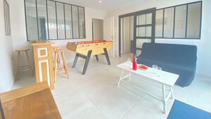 A modern living room with a foosball table, a sofa, and a coffee table. - Spacious house, all comforts, beach and harbour 100 metres away (Plouescat)