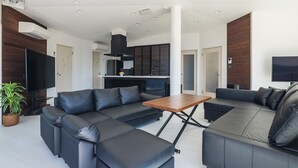 A modern living room with a sectional sofa, a wooden coffee table, and a flat-screen TV. - at SUNSET VILLA INAMI (印南町)