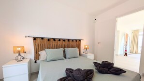 Un dormitorio con una cama, dos mesitas de noche, un cabecero y un espejo.