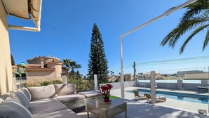 Un patio con un sofá, una mesa de centro y una zona de piscina.