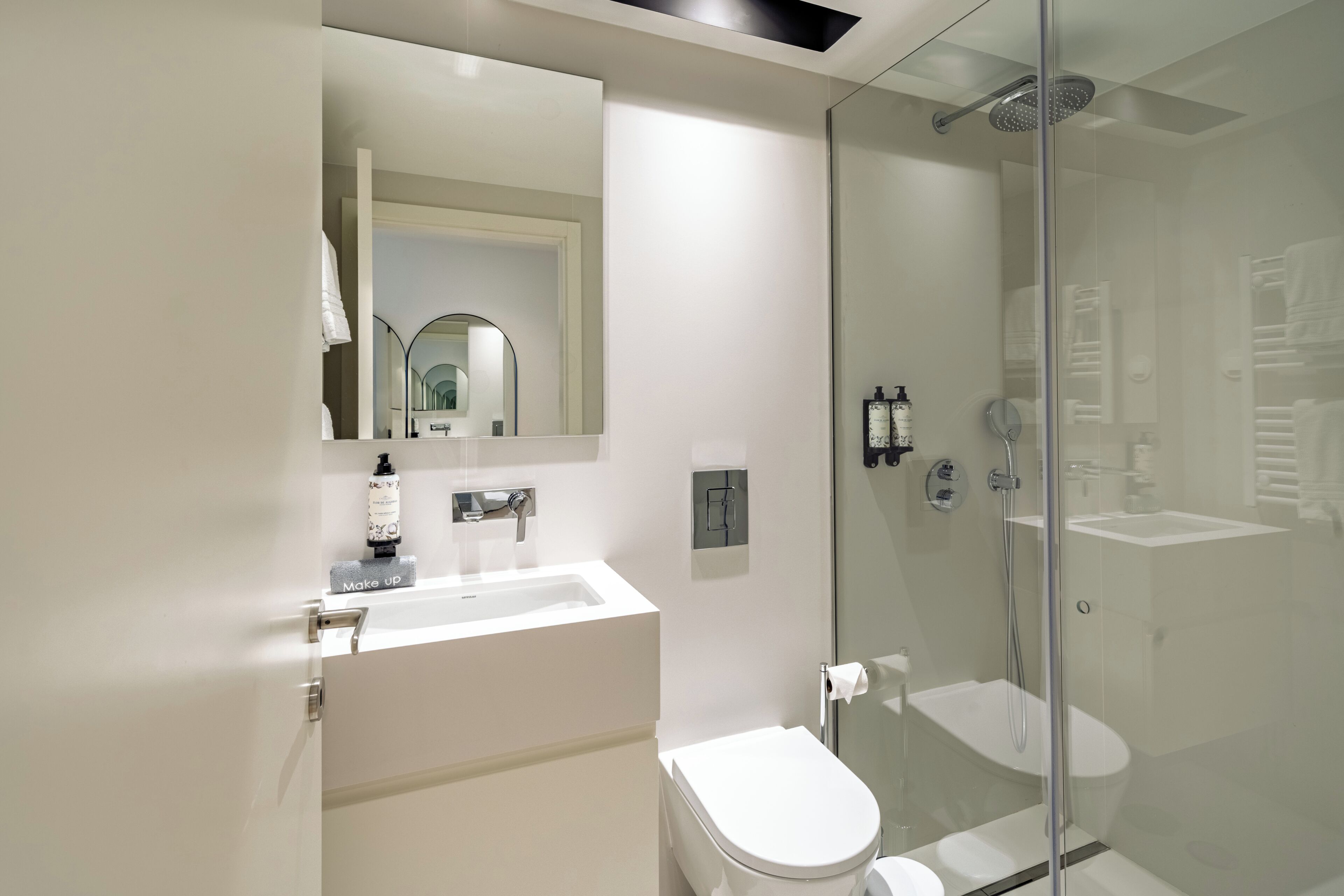 A modern bathroom with a glass-enclosed shower, a white sink, and a toilet.