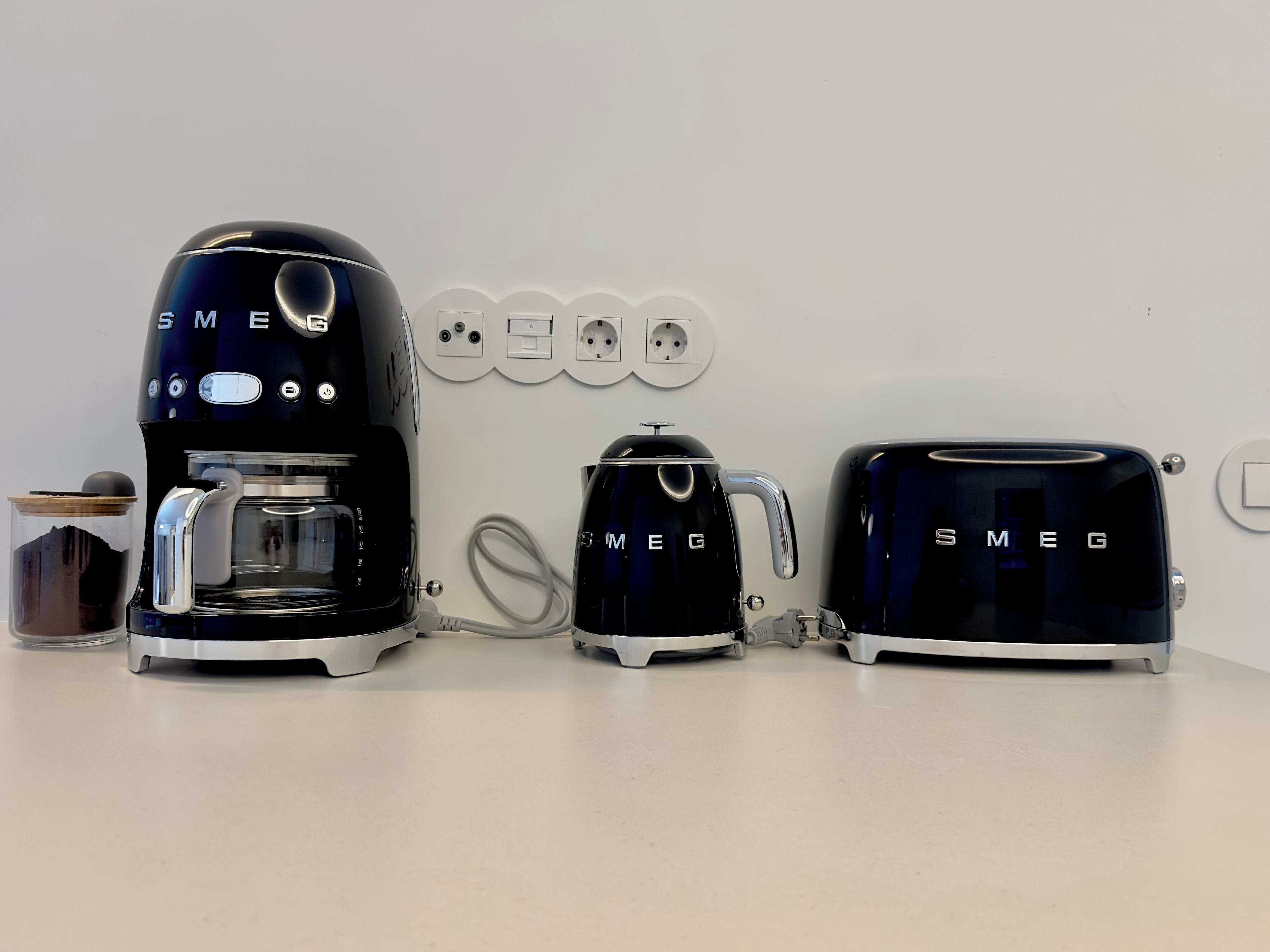 Una cocina con cafetera, tostadora y hervidor sobre una encimera.