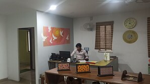 A room with a desk, computer, and a wall clock. - Travelers Hostel  (Guwahati)
