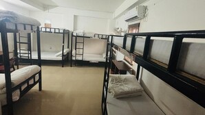 A dormitory room with bunk beds, a desk, and a chair. - Travelers Hostel  (Guwahati)