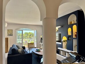 Ein modernes Wohnzimmer mit einer Couch, einem Esstisch und einer Küchenzeile mit Arbeitsfläche und Schränken.